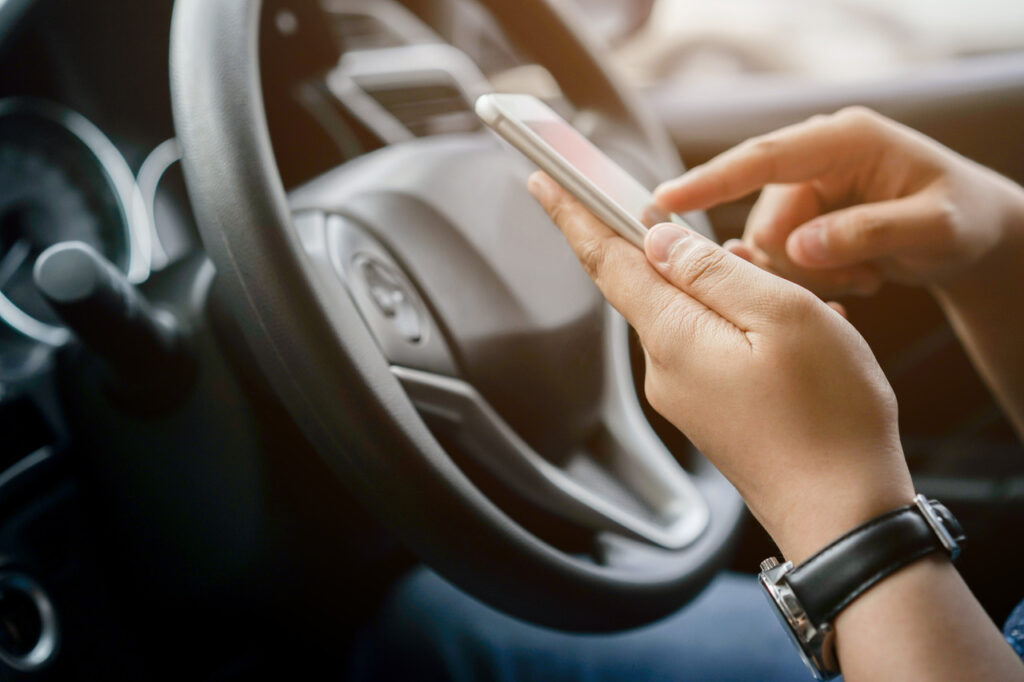 close up driver woman hand holding smartphone for using GPS navigation of travel destination and swipe for reading data on web browser or texting message online for contact while parking